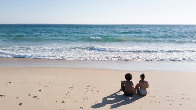 Couple assis sur la plage de sable fin