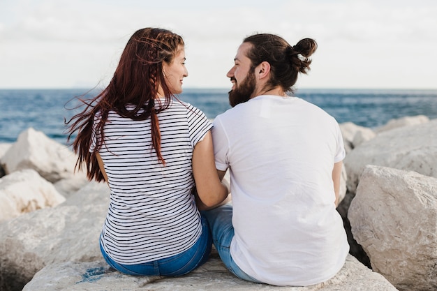 Couple assis sur les rochers à la mer
