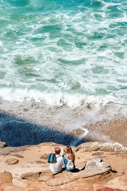 Photo gratuite un couple assis sur les rochers et regardant l'océan de san diego, usa