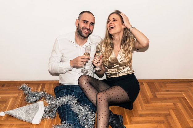 Couple assis sur le sol avec des coupes à Champagne