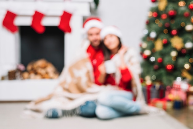 Couple assis sur le sol près d&#39;un arbre de Noël