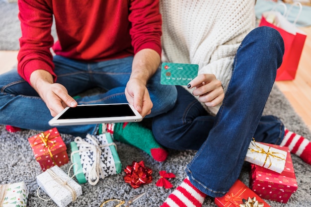 Photo gratuite couple assis avec tablette et carte de crédit au sol