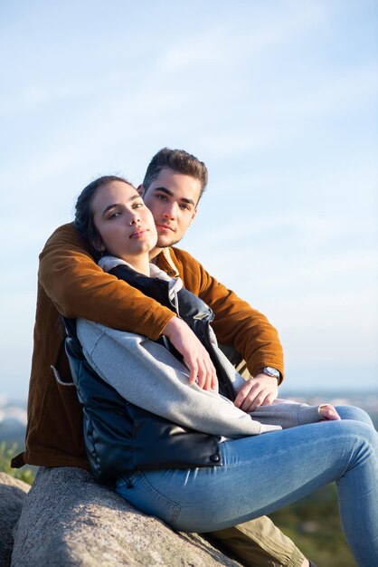 Couple attentionné se reposant après une randonnée en automne. Homme et femme en vêtements décontractés assis au sommet, regardant la caméra. Nature, activité, concept de passe-temps