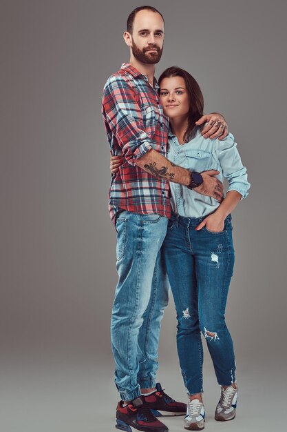 Couple attrayant, homme barbu et fille brune se câlinant dans un studio. Isolé sur un fond gris.