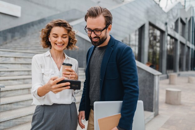 Couple attrayant d'homme et de femme dans le centre-ville urbain, tenant le téléphone et regardant