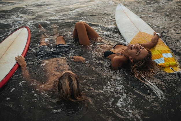 Couple au repos dans l'eau avec des planches de surf