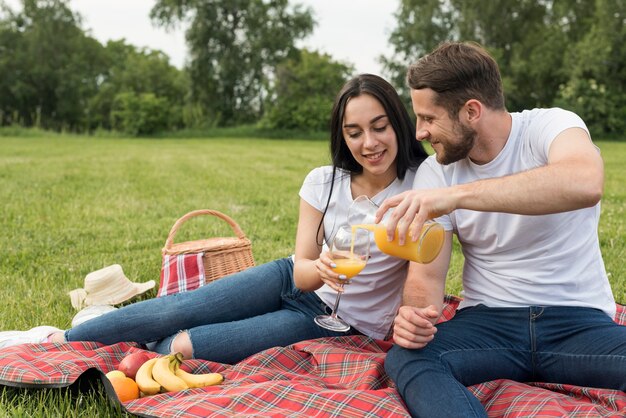 Couple ayant du jus d&#39;orange sur une couverture de pique-nique