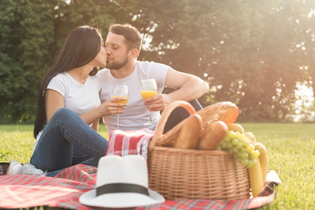 Photo gratuite couple ayant du jus d'orange sur une couverture de pique-nique