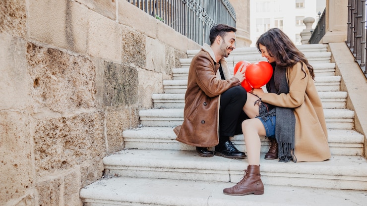 Photo gratuit couple avec des ballons assis sur les marches