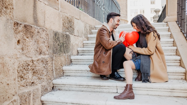 Couple avec des ballons assis sur les marches