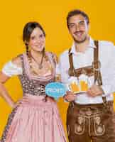 Photo gratuite couple bavarois souriant tenant des pancartes oktoberfest