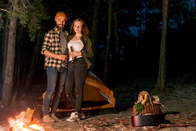 Couple buvant et regardant le feu de camp