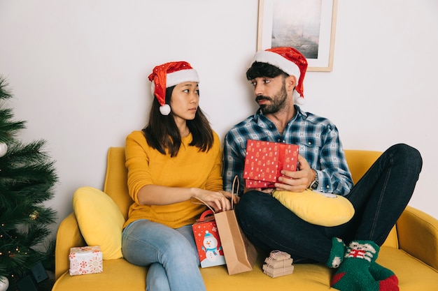 Couple avec des cadeaux de Noël sur le canapé