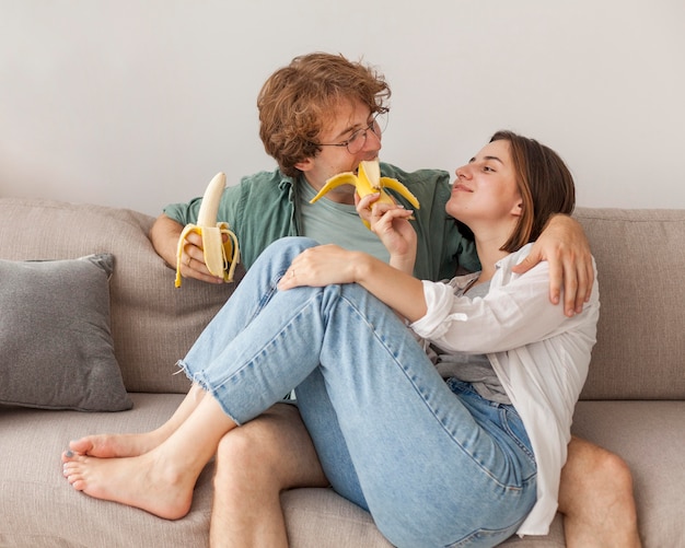 Couple sur canapé, manger des bananes