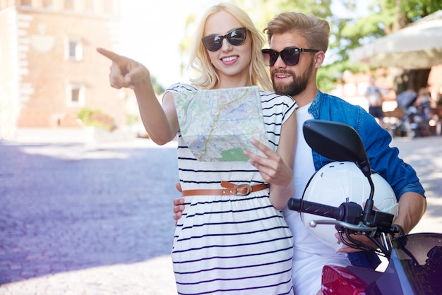 Couple avec carte et scooter à la ville