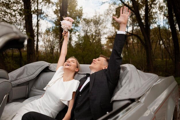 Couple célébrant dans leur voiture juste mariée