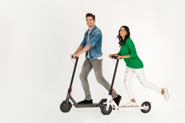 Un couple à cheval sur un scooter électrique isolé sur fond de studio blanc