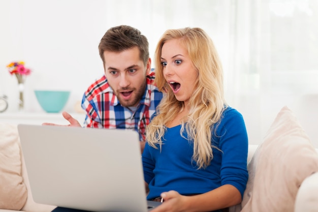 Couple choqué à la recherche d'un ordinateur portable contemporain