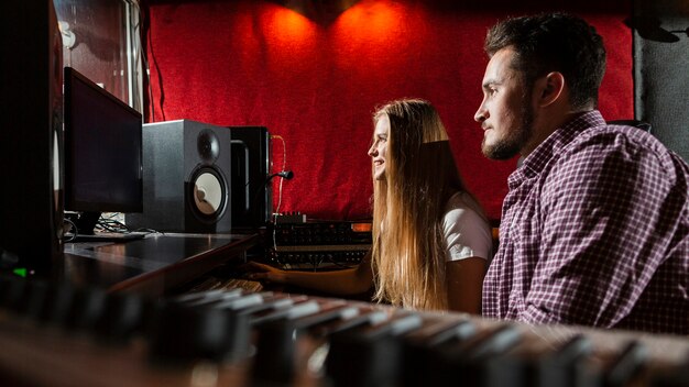 Couple sur le côté en regardant les écrans en studio