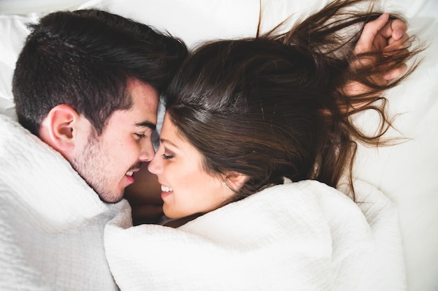 Couple couché dans le lit et enveloppé jusqu&#39;au cou