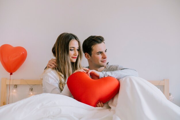 Couple avec coussin de coeur au lit