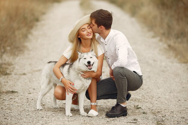 Couple dans un champ d'automne jouant avec un chien