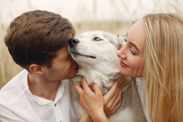 Photo gratuite couple dans un champ d'automne jouant avec un chien