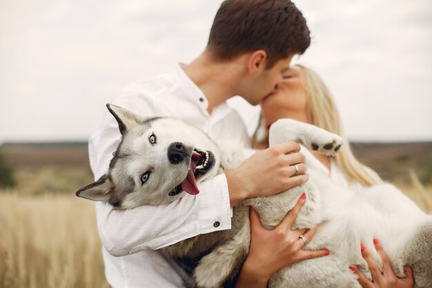 Couple dans un champ d'automne jouant avec un chien