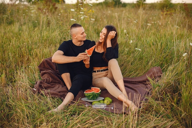 Couple dans un champ. Femme dans un chemisier noir. Les gens avec de la pastèque.