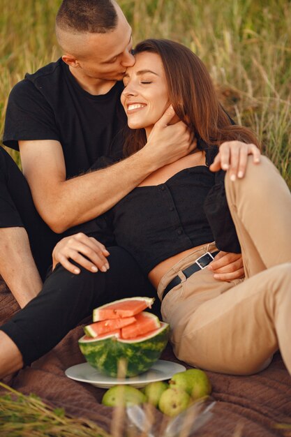 Couple dans un champ. Femme dans un chemisier noir. Les gens avec de la pastèque.