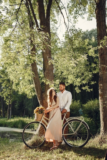 Couple dans un parc d'été. Les gens avec vélo vintage. Fille au chapeau.