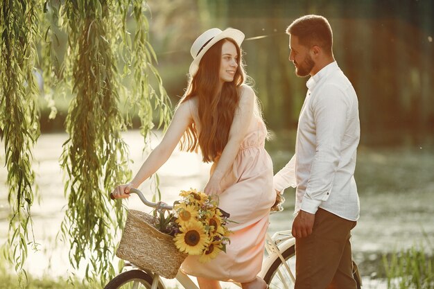 Couple dans un parc d'été. Les gens avec vélo vintage. Fille au chapeau.