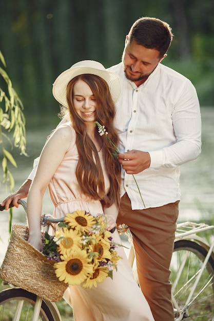 Couple dans un parc d'été. Les gens avec vélo vintage. Fille au chapeau.