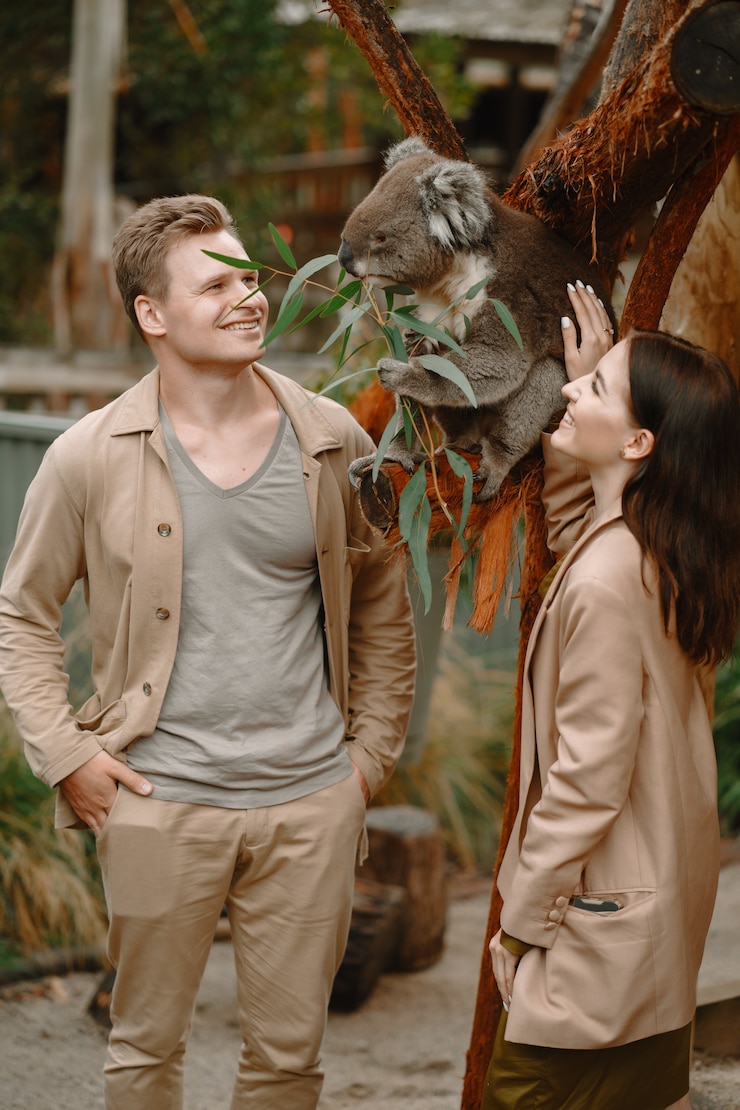 Photo gratuit couple dans la réserve joue avec un koala