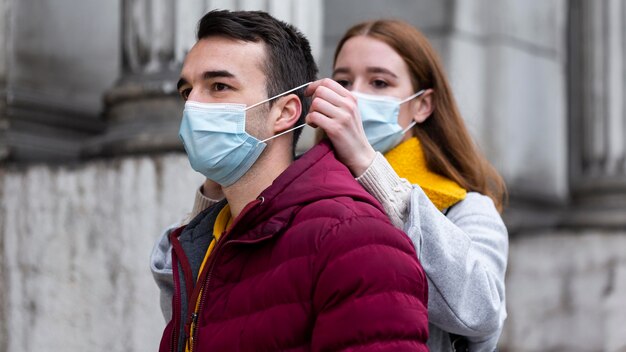 Couple dans la ville portant des masques médicaux ensemble