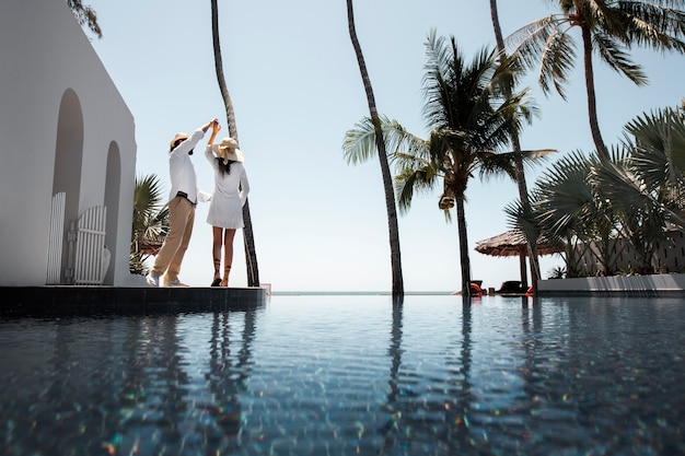 Couple dansant au bord de la piscine pendant les vacances