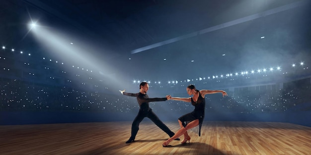 Couple de danseurs exécutent la danse latine sur une grande scène professionnelle danse de salon