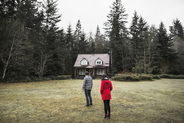 Photo gratuite couple debout près de la cabane de la forêt