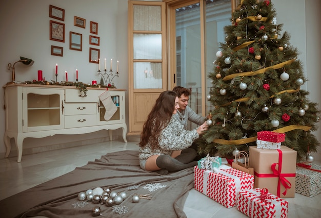 Couple, décoration, arbre noël, reposer plancher