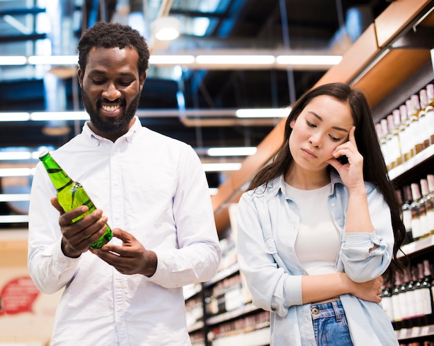 Photo gratuite couple en désaccord sur la bière à l'épicerie