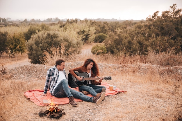 Couple de détente en plein air à côté d'un feu de camp