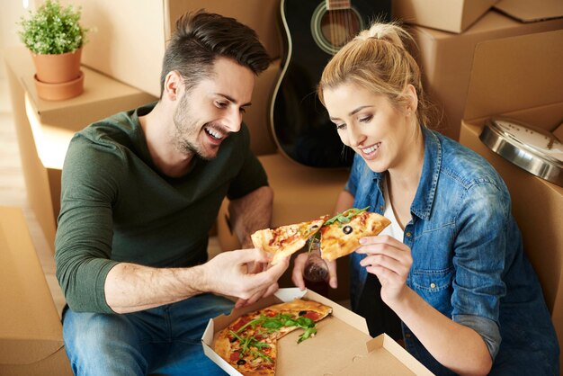 Couple eating pizza à côté de cartons de déménagement