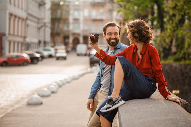 Couple élégant amoureux assis dans la rue lors d'un voyage romantique, prenant une photo