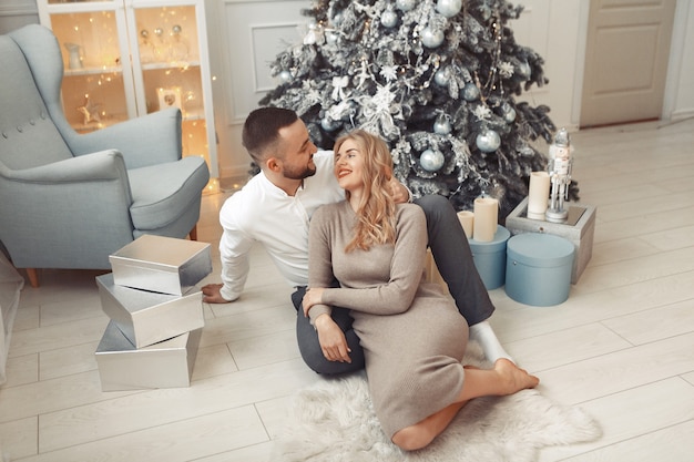 Couple élégant assis à la maison près de l'arbre de Noël