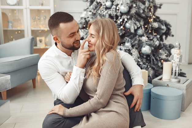 Couple élégant assis à la maison près de l'arbre de Noël