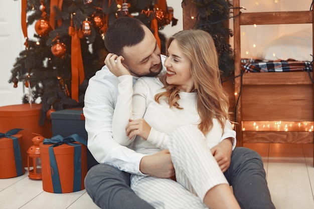 Couple élégant assis à la maison près de l'arbre de Noël