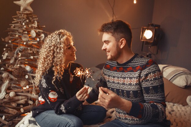 Couple élégant assis à la maison près de l'arbre de Noël