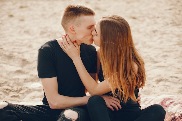 Un couple élégant et beau en vêtements noirs passe un bon moment sur la plage