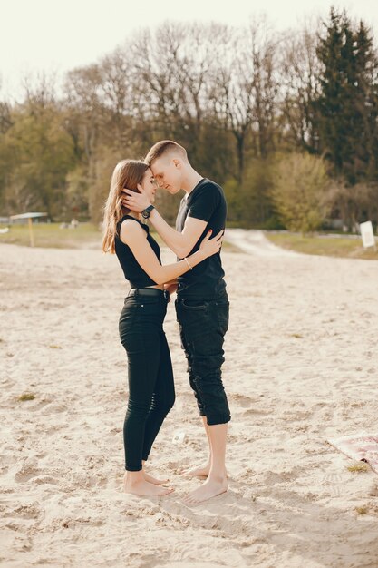 Un couple élégant et beau en vêtements noirs passe un bon moment sur la plage