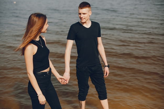 Un couple élégant et beau en vêtements noirs passe un bon moment sur la plage